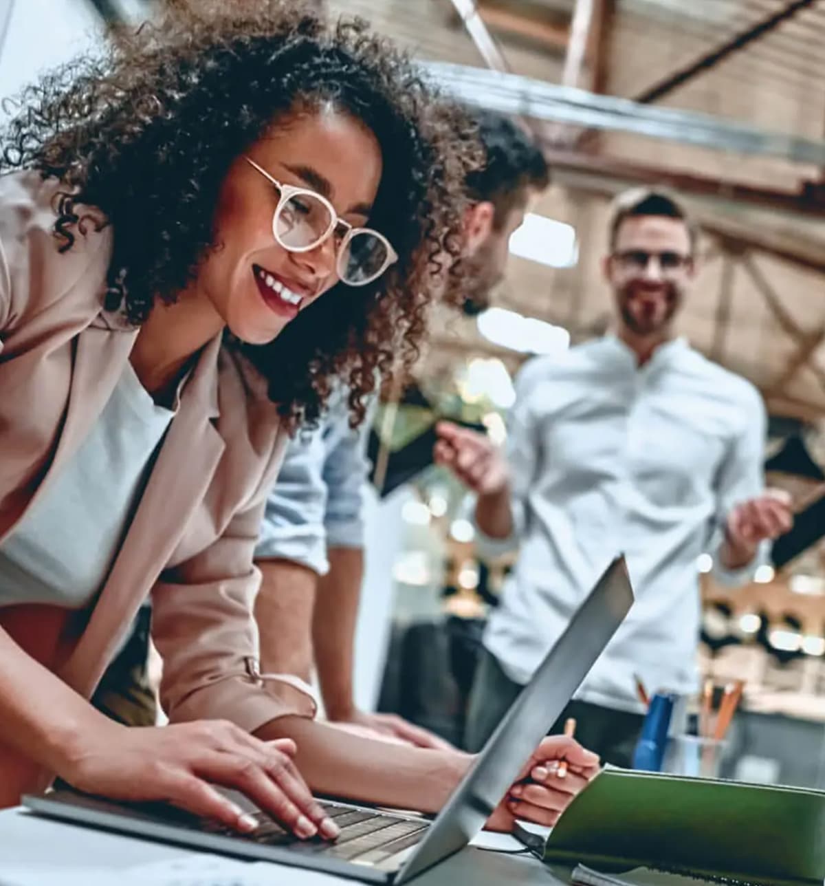 Employee using laptop around other co workers talking